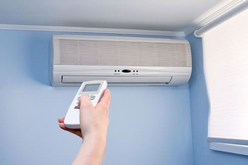 Homeowner adjusting ductless mini-split settings with remote
